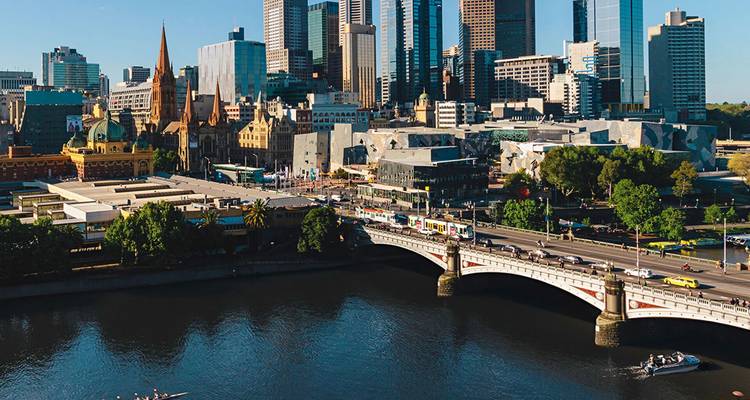 Skyline des Melbourne CBD, das sich im Yarra River mit der Princes Bridge im Vordergrund an einem klaren Morgen spiegelt.