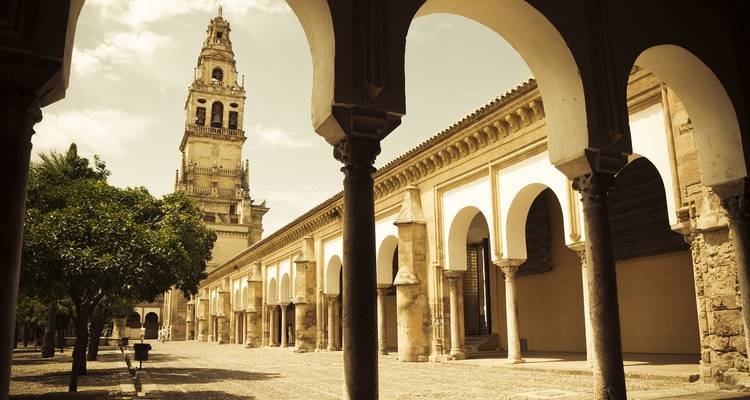 Hofansicht der Moschee-Kathedrale von Córdoba mit Bögen, die den historischen Glockenturm rahmen.
