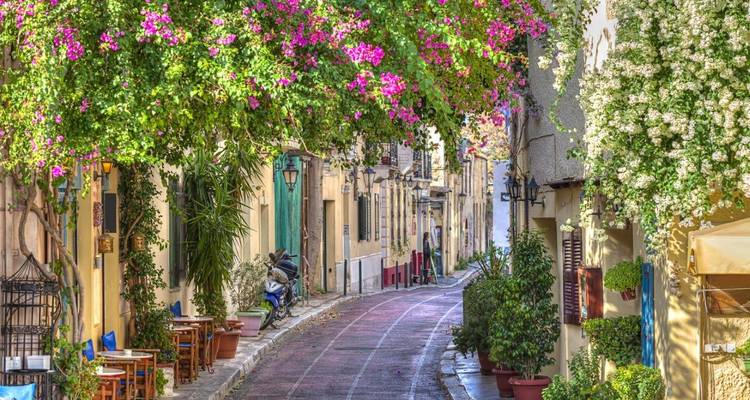 Charmante smalle straat in Athene met bougainville, cafes en kleurrijke huisjes.