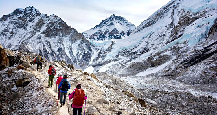 Los trekkers siguen un camino de montaña accidentado hacia el macizo nevado del Everest y el glaciar de Khumbu.
