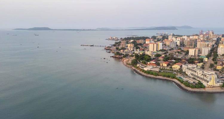 Panorama de drone del horizonte costero de Conakry y la península que se adentra en el tranquilo mar azul.
