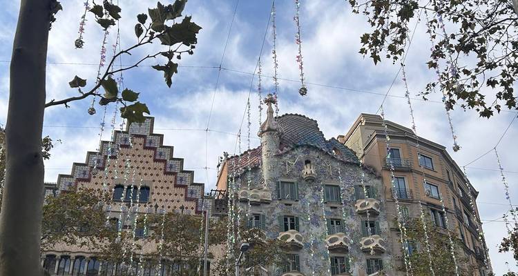 Casa Batlló et les bâtiments voisins drapés de guirlandes de cristal festives sous un ciel dégagé.