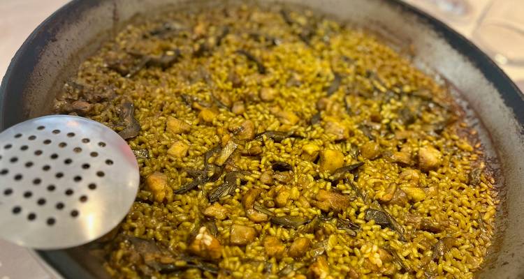 Gros plan d'une poêle à paella traditionnelle remplie de riz, de poulet et de légumes prête à être servie.