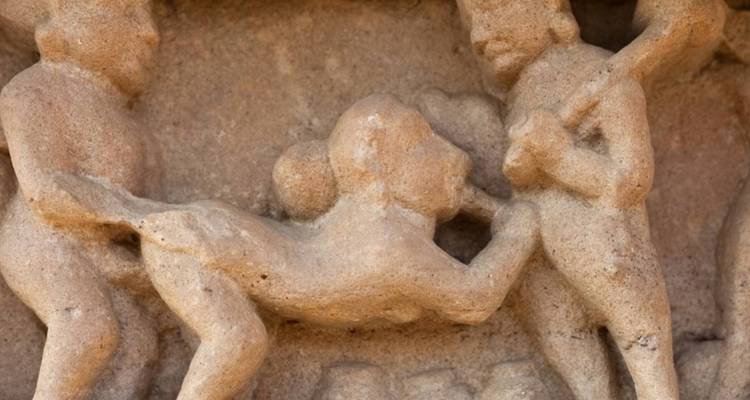 Nahaufnahme eines antiken Sandstein-Reliefs, das menschliche und tierische Figuren an einer Tempelwand in Khajuraho darstellt.