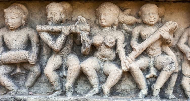 Ein detailliertes Fries zeigt Musiker und Tänzer, die in hohem Relief auf einer Tempelpaneele gemeißelt sind.