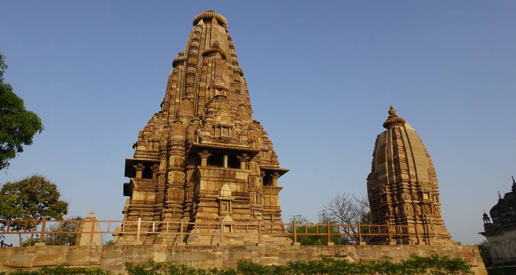 Ein Tempel im Nagara-Stil aus Sandstein erhebt sich gegen einen klaren blauen Himmel mit einem kleineren Schrein daneben.