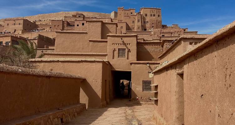 Aarden steegje dat leidt naar het versterkte dorpje Aït Benhaddou onder een levendige blauwe hemel.