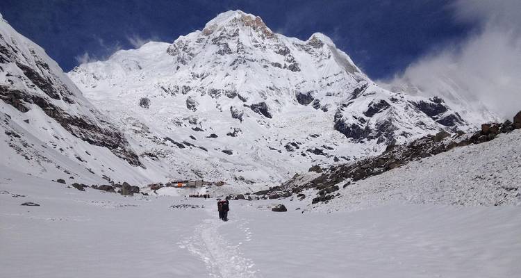 Solotrekker die door diepe sneeuw naar de imposante Annapurna-pieken loopt op een heldere dag.