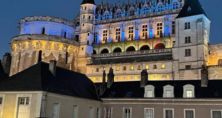 Castillo renacentista iluminado con luces azules y doradas contra el cielo nocturno.