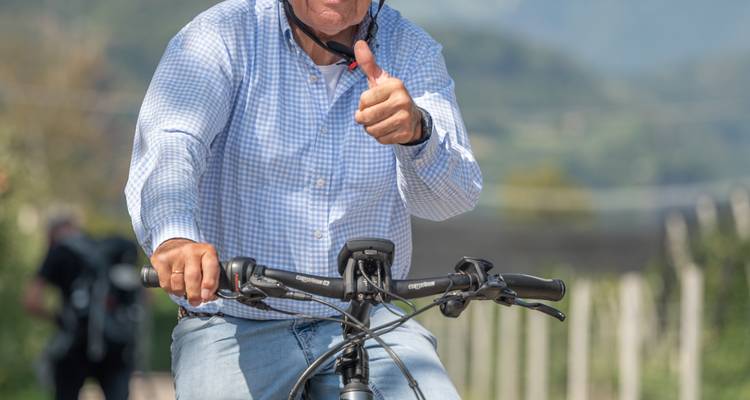 Lächelnder Radfahrer, der während einer Fahrradfahrt an einem sonnigen Tag einen Daumen nach oben zeigt.