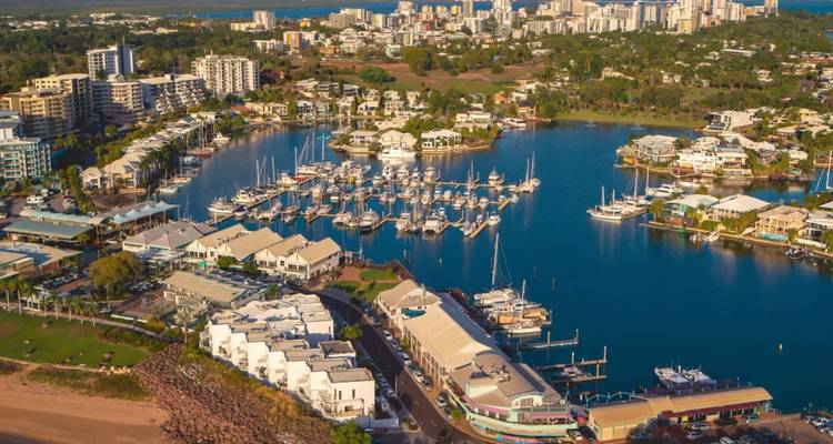 Vista aérea de una marina moderna llena de yates rodeada del skyline de la ciudad y las aguas azules del puerto.