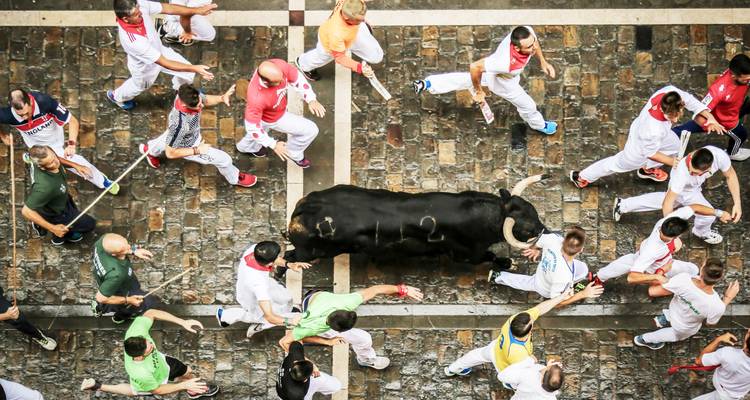 Vue aérienne de coureurs et d'un taureau chargeant lors du célèbre festival de la Course des taureaux à Pampelune