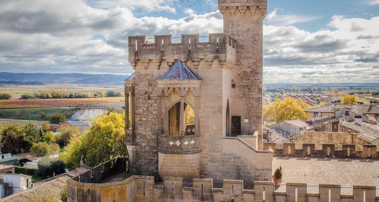 Tour en pierre et remparts du château d'Olite dominant la campagne pittoresque par une journée partiellement nuageuse