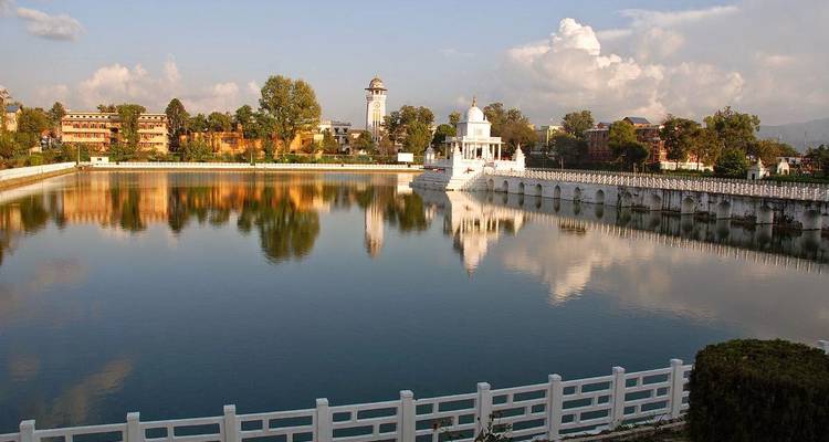 Bassin de réflexion avec pavillon de temple blanc et panorama urbain de Katmandou en arrière-plan