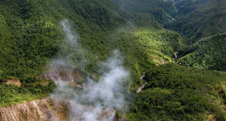 Luchtfoto van stoomende fumarolen en dicht regenwoud in Dominica's vulkanische vallei
