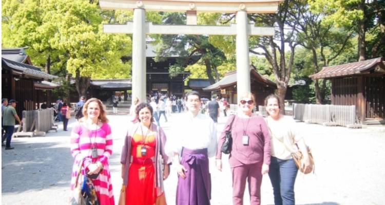 Gruppe von Besuchern, die am Eingang eines hell leuchtenden Torii-Tors bei starker Sonneneinstrahlung posieren, leicht überbelichtet.