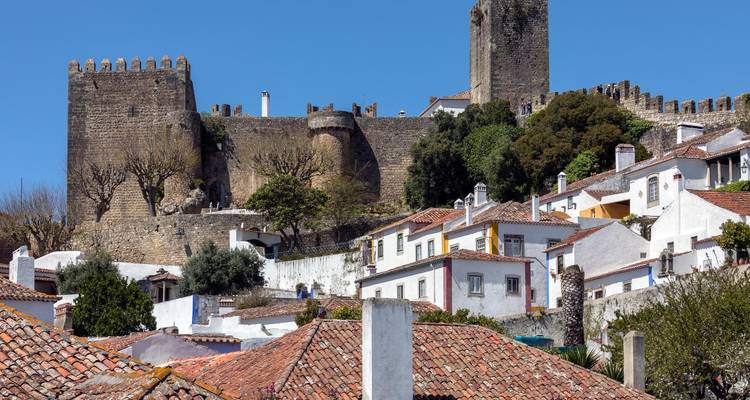 Murallas de piedra y torre del homenaje del castillo de Óbidos que se alzan sobre los tejados de barro cocido
