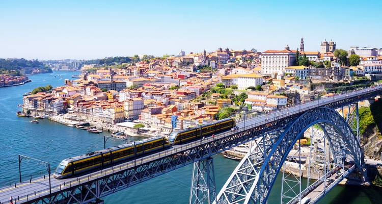 Tren del metro cruzando la cubierta superior del Puente Dom Luís I con el horizonte de Oporto y el río abajo