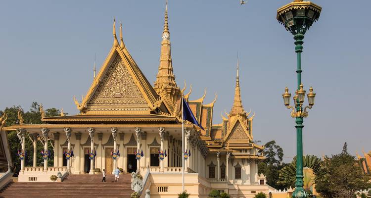 Cambodjaans koninklijk paleis met gouden daken en sierlijke torenspitsen tegen een heldere hemel, gezien vanaf de grote trap.