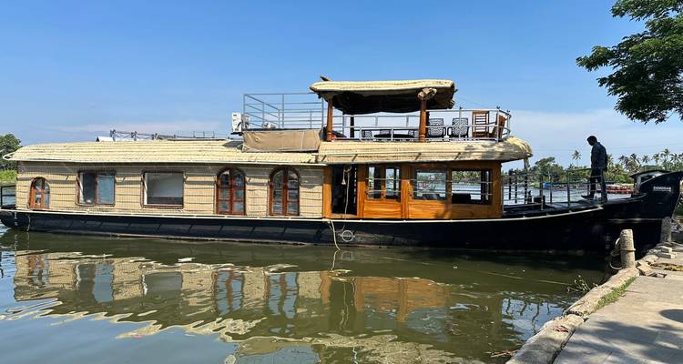 Traditionelles Holzboot, das in einem ruhigen Backwater-Kanal vertäut ist, mit klaren Spiegelungen des Himmels