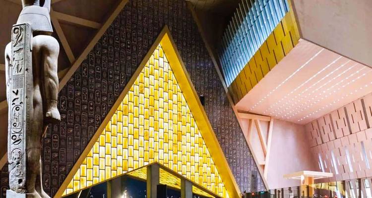 Entrée triangulaire moderne illuminée du Grand Musée égyptien la nuit.