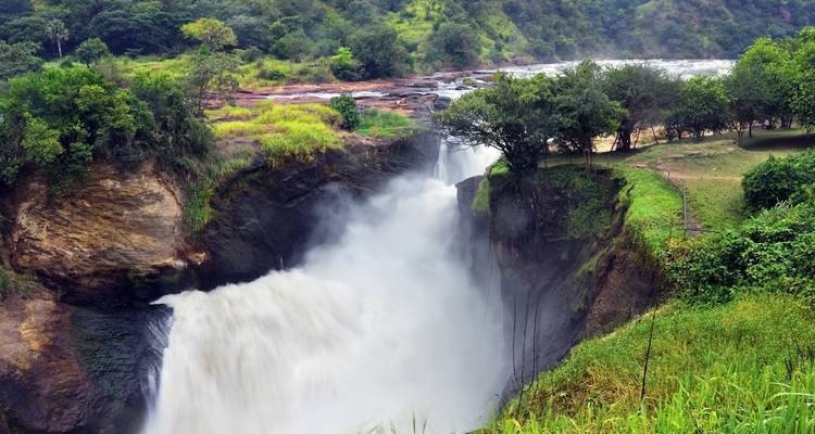 Una cascada potente que se desploma a través de un cañón rocoso estrecho rodeado de exuberante vegetación verde.