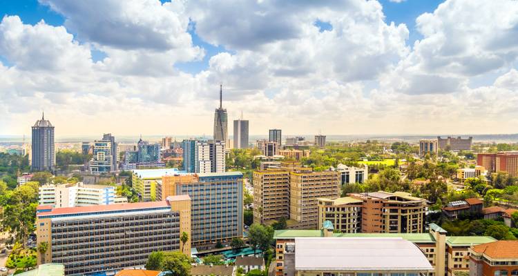 Panoramisch uitzicht op de skyline van Nairobi overdag met moderne wolkenkrabbers omgeven door weelderig groen en dramatische wolken.