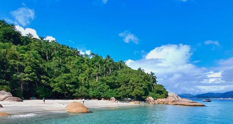 Playa tropical con agua turquesa, rocas de granito y selva exuberante bajo un cielo azul brillante