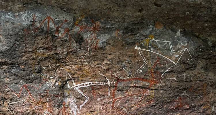 Primer plano de figuras de arte rupestre indígena pintadas en una superficie de piedra rugosa