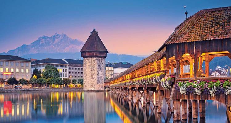 Schemering uitzicht op de Kapelbrug en Watertoren van Luzern die weerspiegeld worden in de Rivier de Reuss.