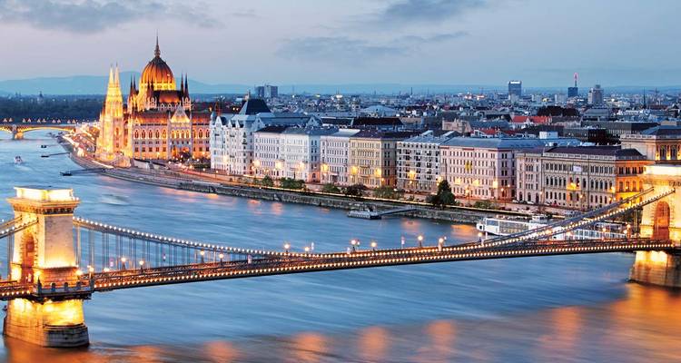 Zwielicht-Panorama von Budapest mit der Kettenbrücke über die Donau und dem in der Ferne beleuchteten Parlamentsgebäude.