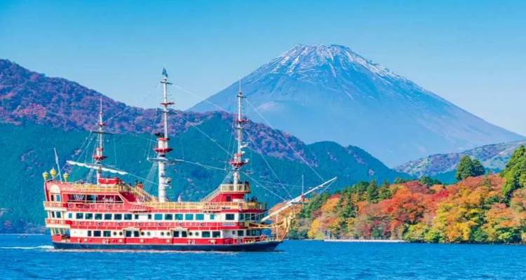 Buntes Piraten-Kreuzfahrtschiff, das auf dem Ashisee segelt, mit dem schneebedeckten Berg Fuji im Hintergrund aufragend.