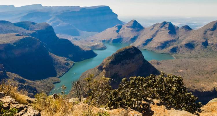 Vue panoramique étendue d'un réservoir turquoise sinueux situé parmi des crêtes montagneuses accidentées et brumeuses et des vallées.