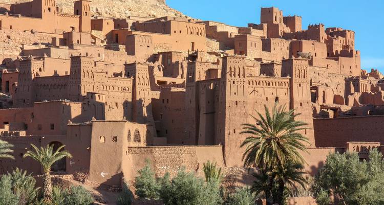 Vue panoramique du village fortifié aux couleurs terracotta d'Aït Benhaddou avec des palmiers en contrebas