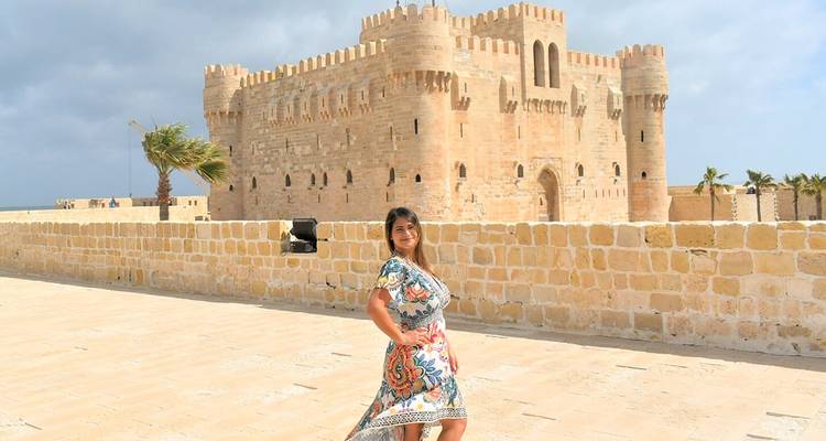 Mujer posando frente a los muros y torres de piedra arenisca de la Ciudadela de Qaitbay en Alejandría.