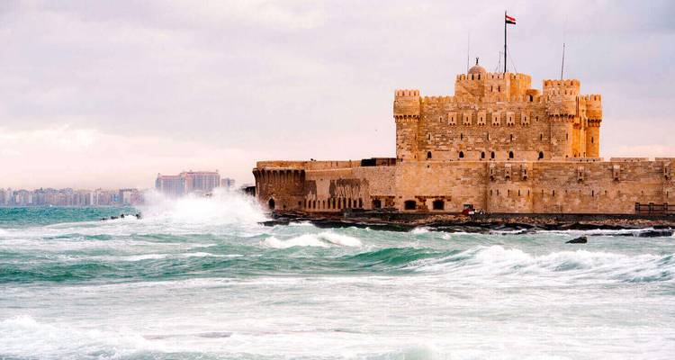 Las olas se estrellan contra los muros de la Ciudadela de Qaitbay de Alejandría bajo un cielo tormentoso.