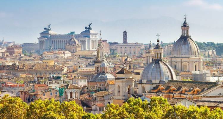 Imposant panorama van Rome vol met koepels, torenspitsen en oude monumenten omgeven door groene boomtoppen.