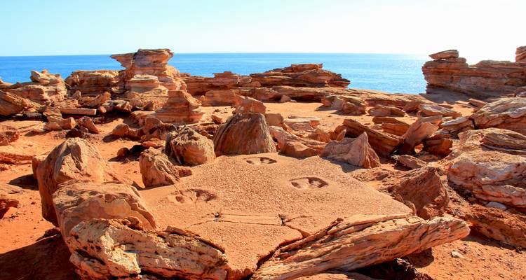 Gefossiliseerde dinosaurusvoetafdrukken in rood zandsteengesteente aan de kust van Broome