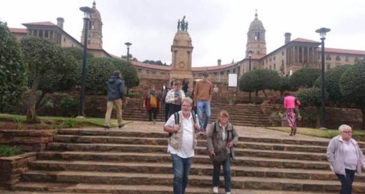 Des touristes descendant les escaliers dans les jardins de l'Union Buildings par un jour nuageux