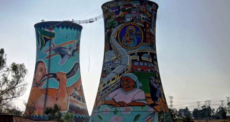 Deux grandes tours de refroidissement peintes à Soweto ornées de murales colorées sur un ciel pâle