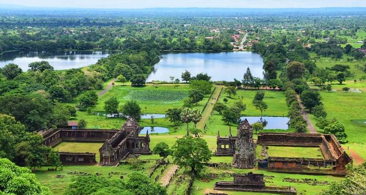 Vista desde la colina sobre el antiguo complejo de templos jemeres de Wat Phou con lagos y vegetación alrededor.