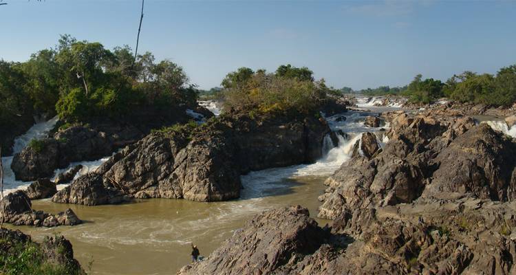 Lecho rocoso accidentado con múltiples torrentes de agua lodosa bajo un cielo azul.