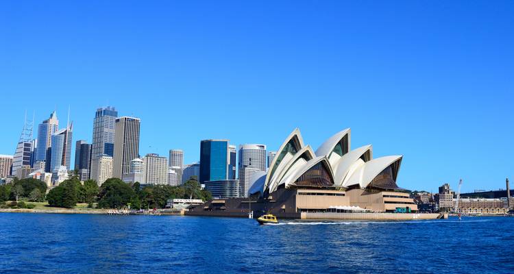Le célèbre Opéra de Sydney et la skyline moderne vus à travers les eaux bleues du port de Sydney par une journée ensoleillée et dégagée.