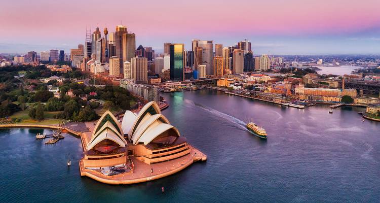 Le mythique Opéra de Sydney et la ligne d'horizon du port au lever du jour avec des teintes de ciel pastel