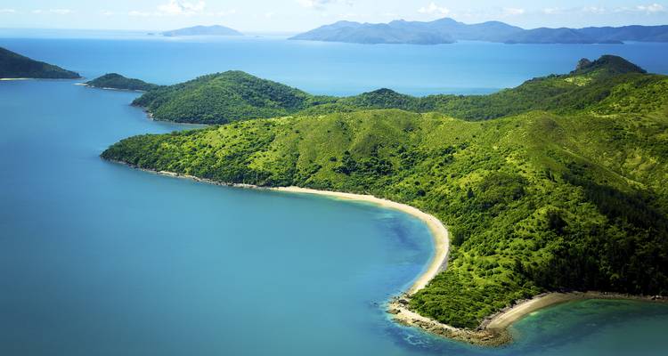 Vue aérienne panoramique d'îles verdoyantes et luxuriantes avec des baies aux plages de sable blanc incurvées, entourées par les eaux turquoise des Whitsundays.