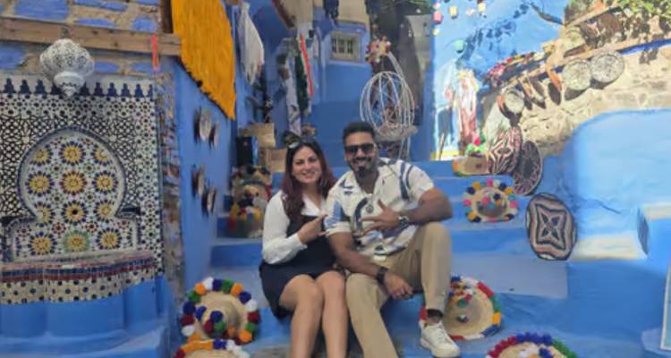 Deux visiteurs posent sur les escaliers bleus décorés de la médina de Chefchaouen, entourés d'artisanat coloré.