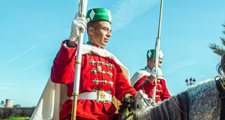 Des gardes royaux en uniforme à cheval vêtus de tuniques rouge vif lors d'un défilé cérémonial.