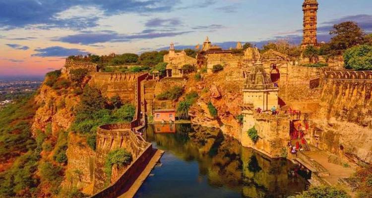 Panoramisch zonsondergangzicht op het Chittorgarh Fort complex gespiegeld in een waterreservoir.