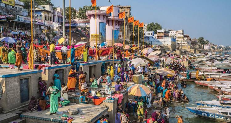 Multitudes de gente colorida se reúnen en los animados ghats de Varanasi, bañándose y subiendo a botes a lo largo del río Ganges.