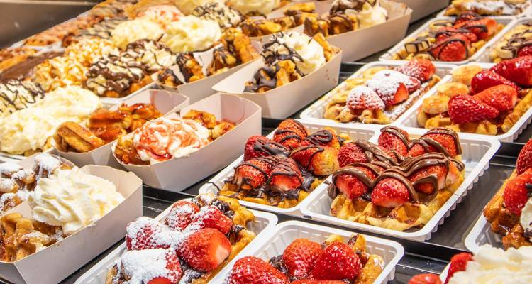 Kleurrijke display van Belgische wafels bedekt met aardbeien, chocolade en slagroom.